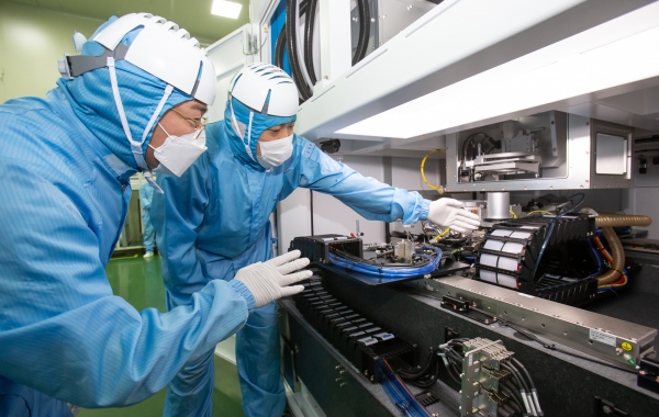 삼성전자 직원(좌)과 이오테크닉스 직원(우)이 양사가 공동 개발한 반도체 레이저 설비를 함께 살펴보고 있다. 사진=삼성전자